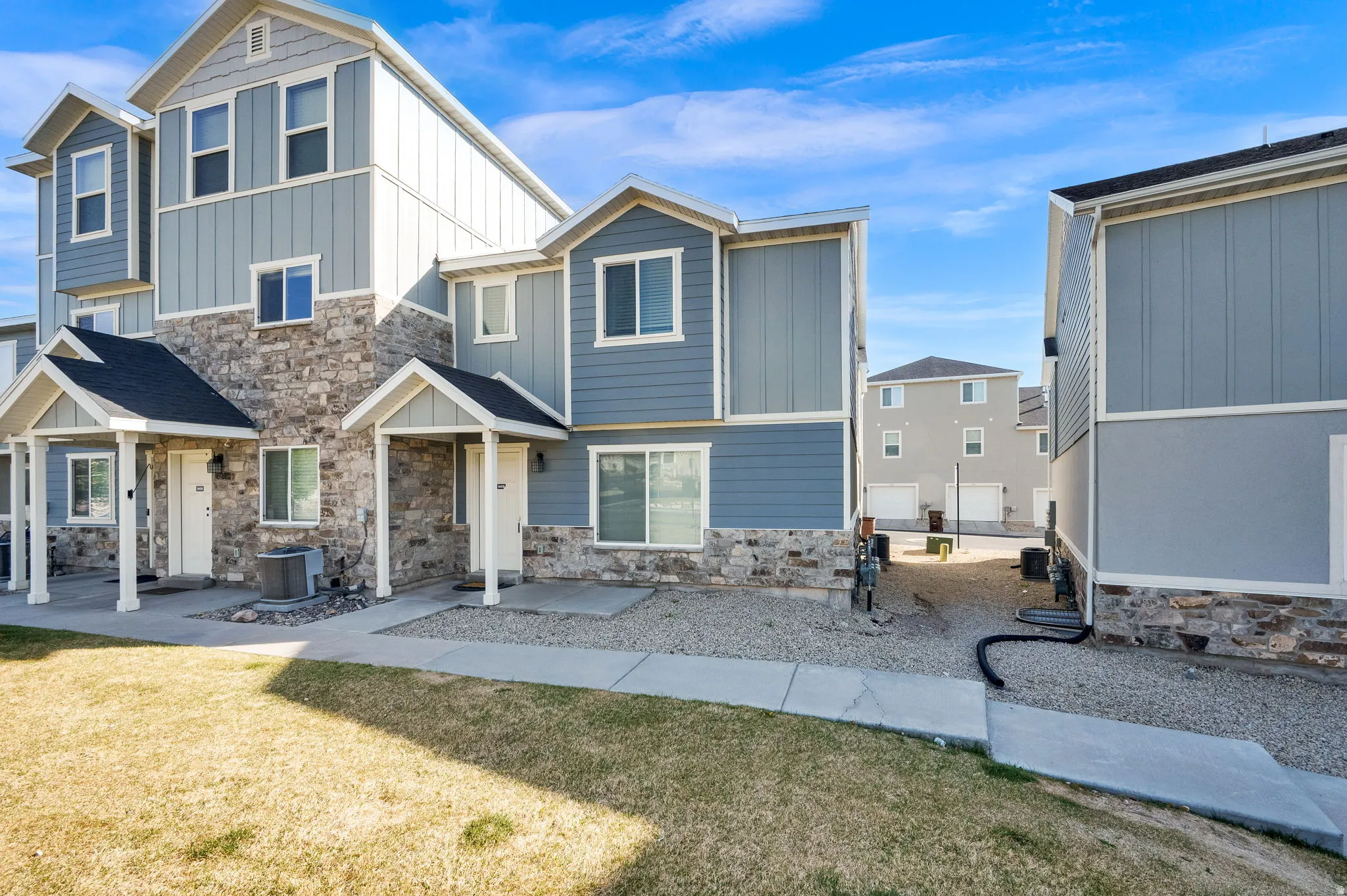View of front of property featuring board and batten siding, stone siding, and a front lawn