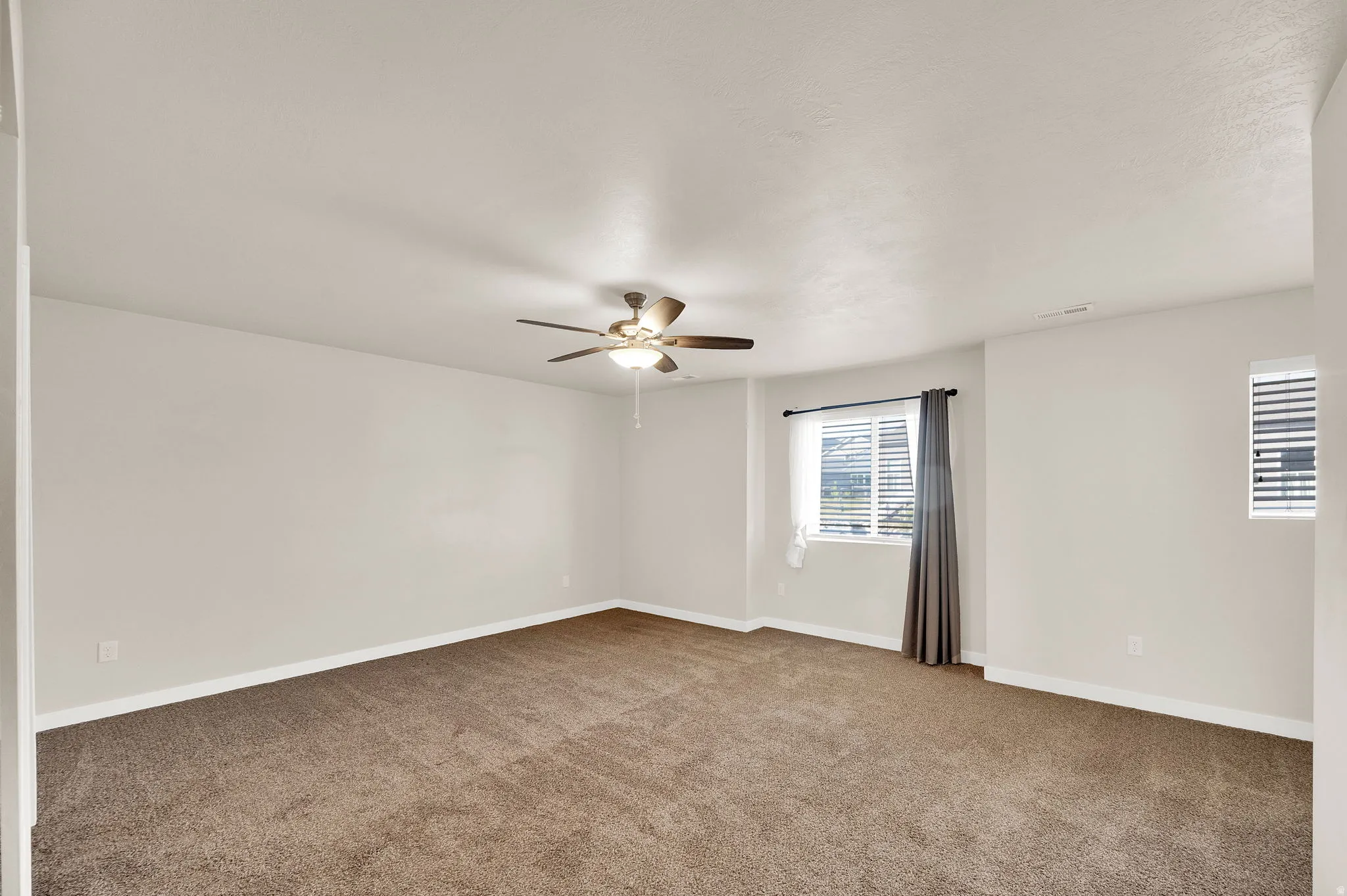 Carpeted spare room featuring baseboards and ceiling fan