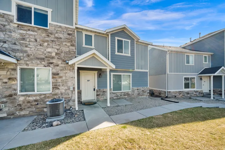 View of front of home with stone siding, a front yard, and board and batten siding