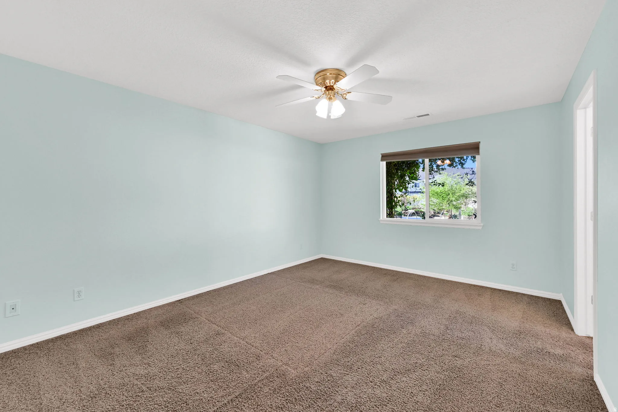 Spare room featuring dark colored carpet and ceiling fan