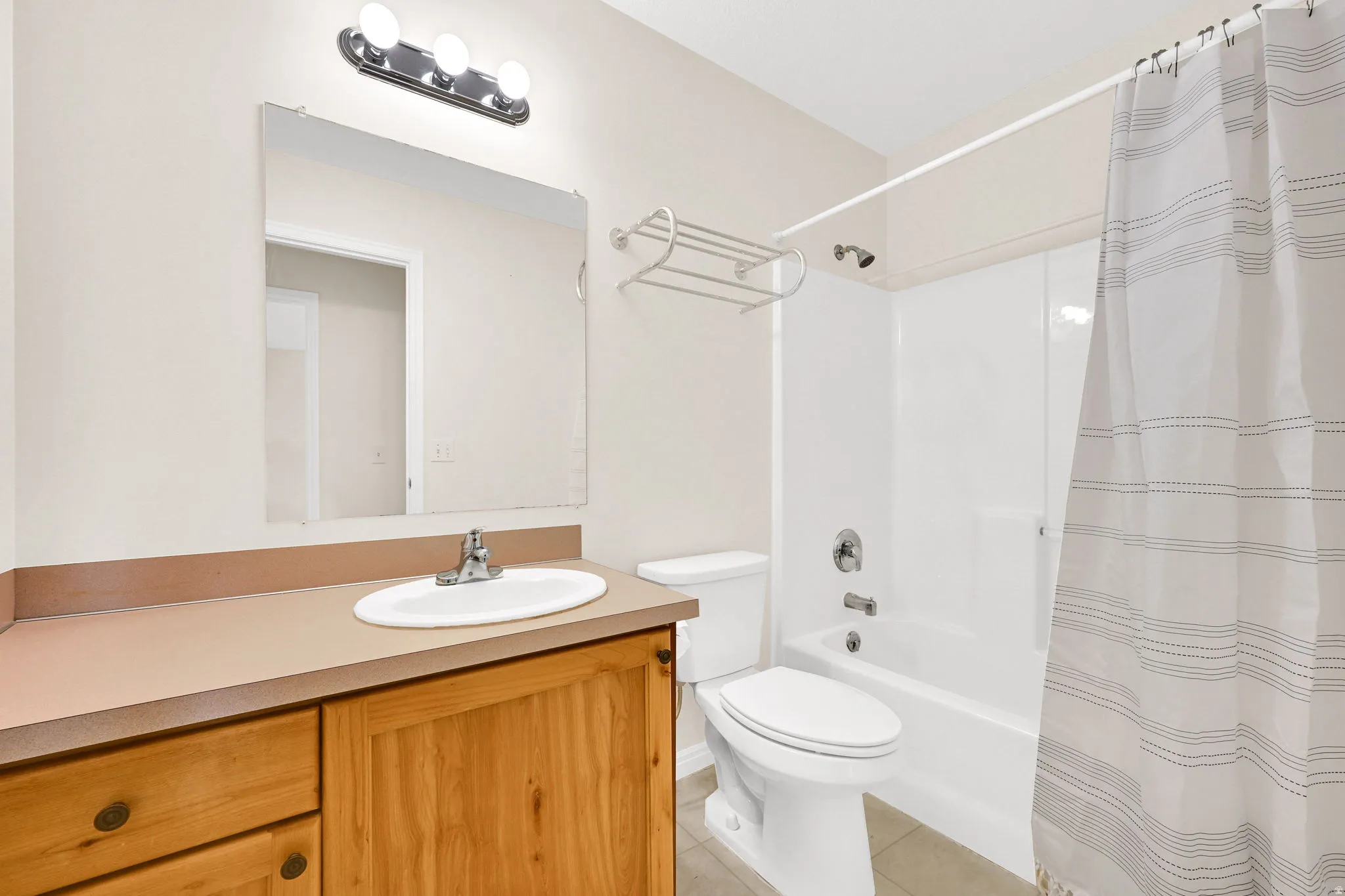 Full bath featuring vanity, light tile patterned flooring, and shower / bath combo
