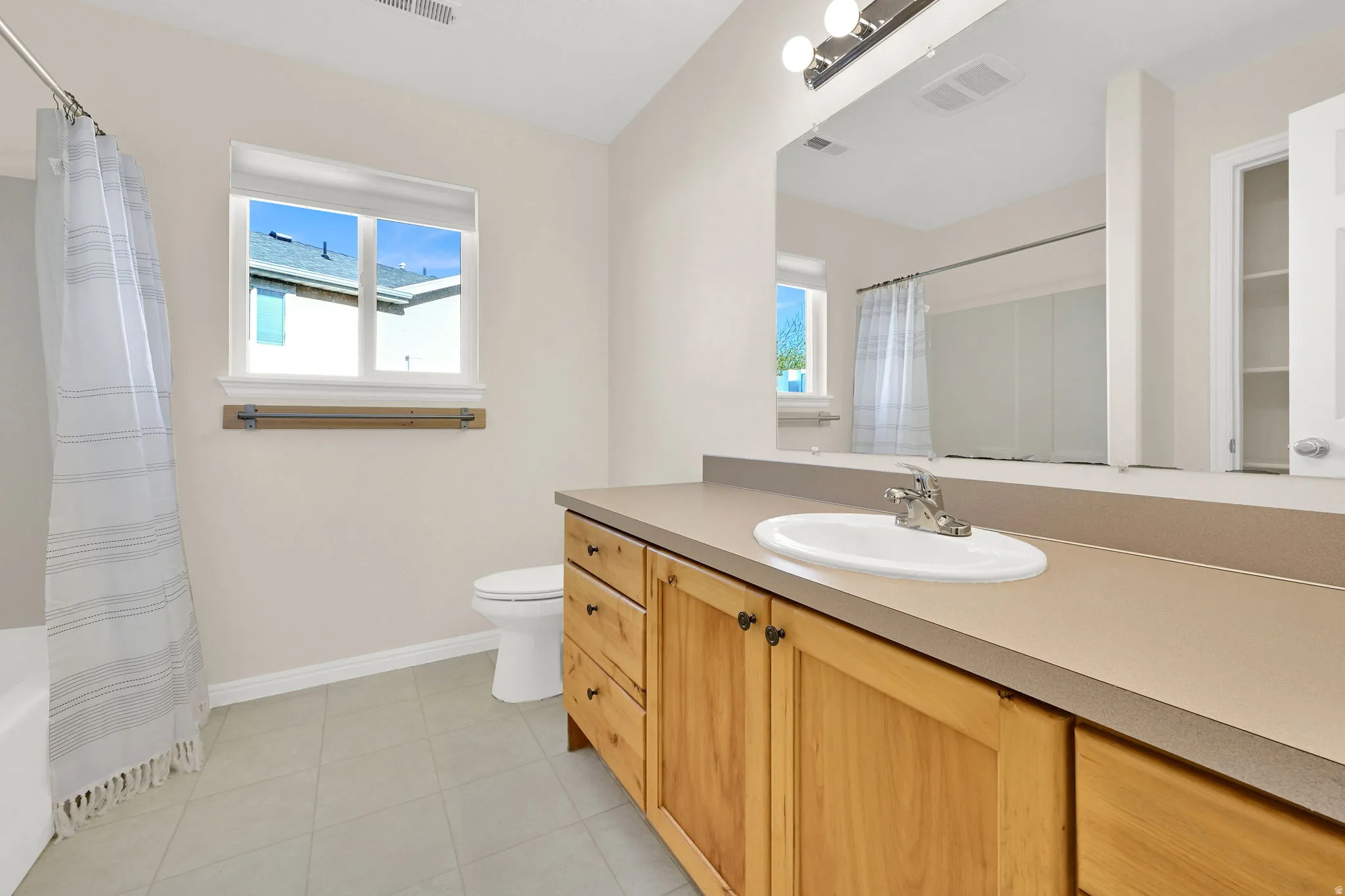 Primary Bathroom with vanity, plenty of natural light, and light tile patterned floors