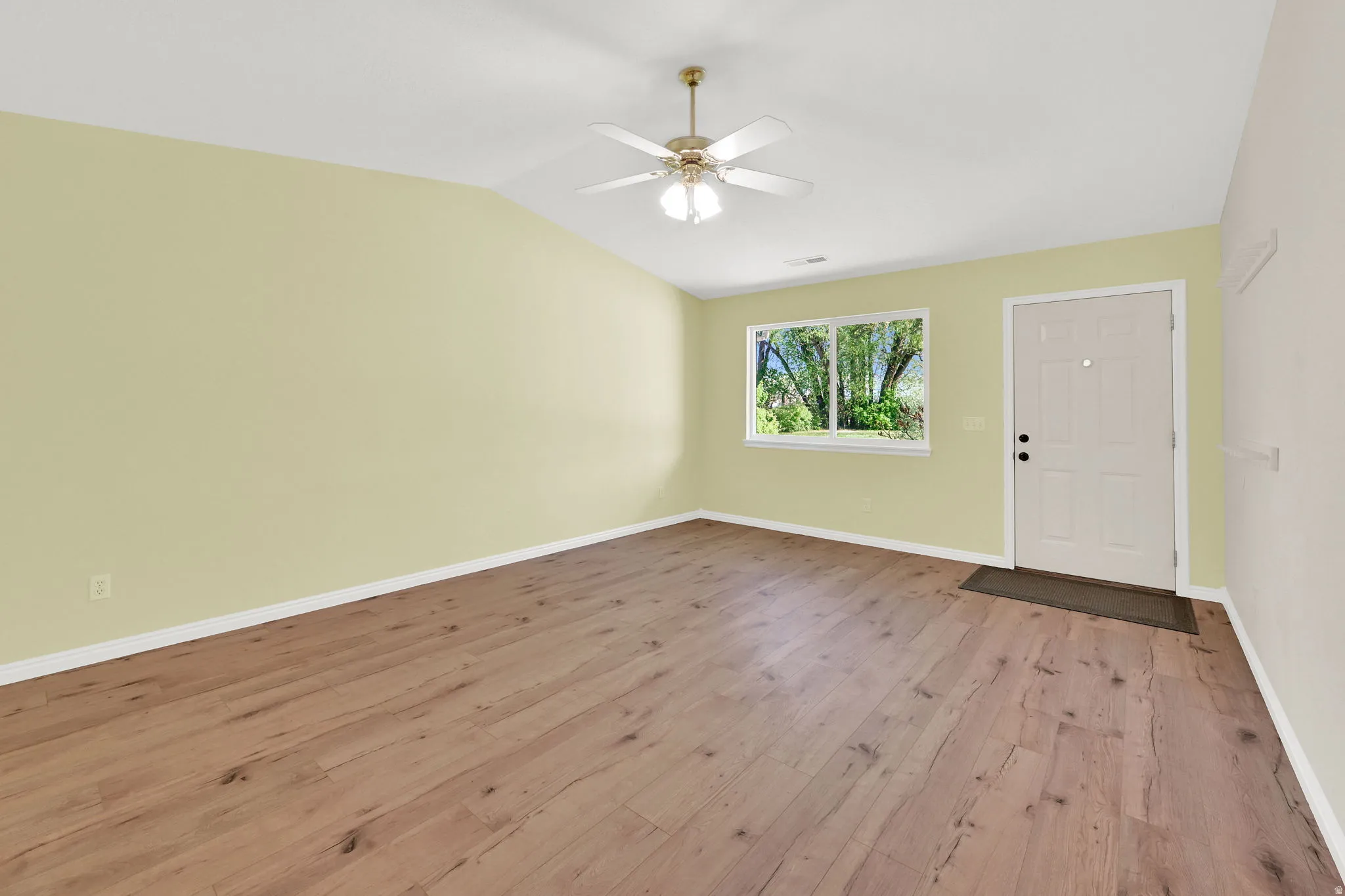 Foyer with light wood-style flooring, a ceiling fan, and lofted ceiling