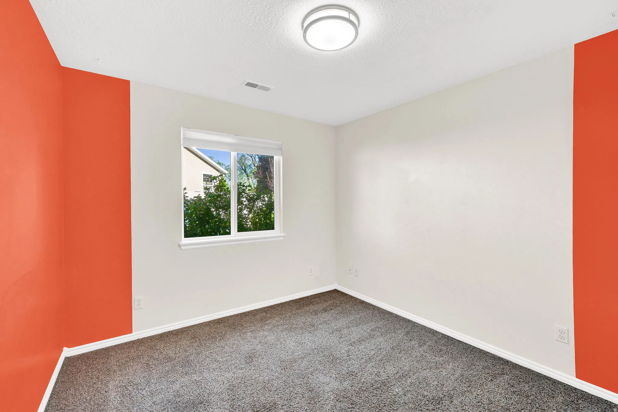 Empty room featuring dark colored carpet and a textured ceiling