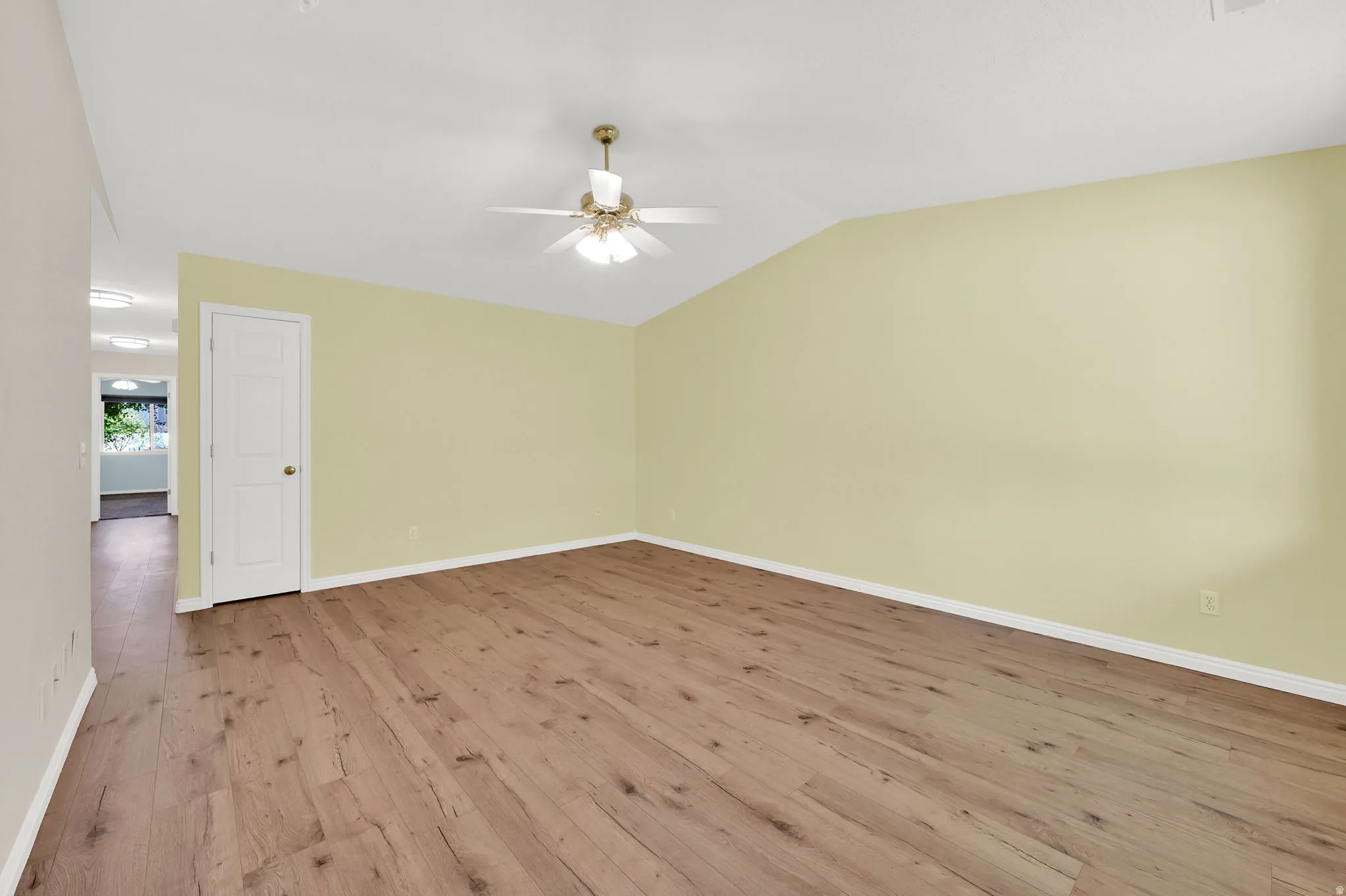Unfurnished room featuring wood finished floors, ceiling fan, and vaulted ceiling