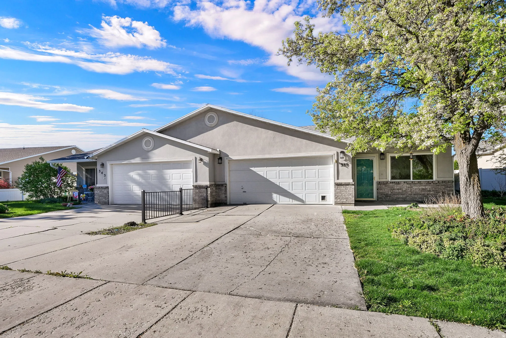 Ranch-style home with stucco siding, a garage, driveway, and brick siding