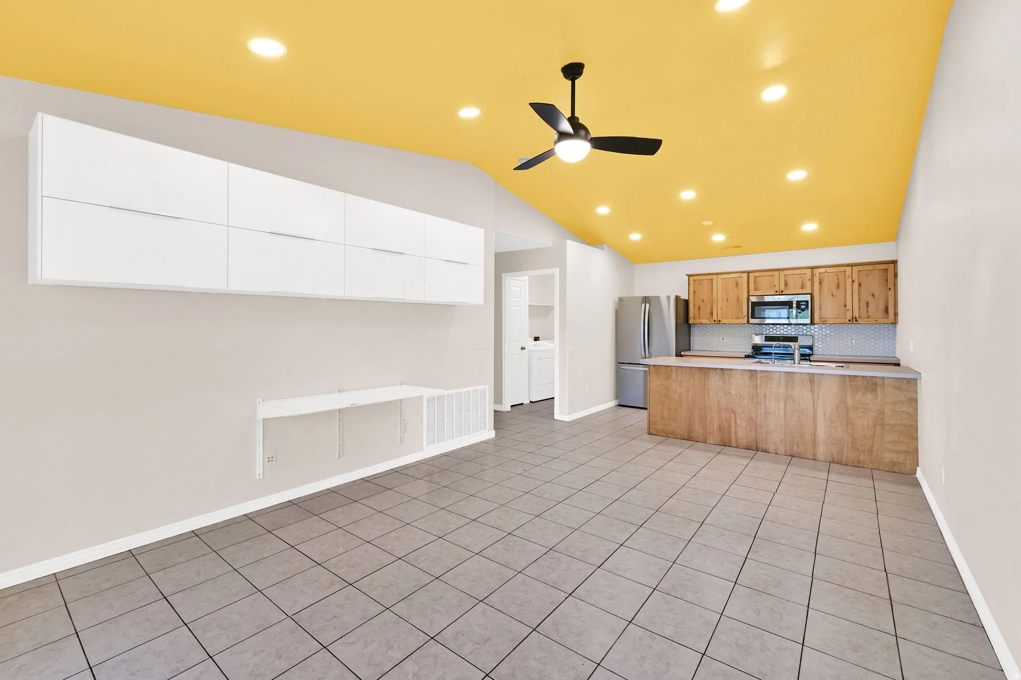 Kitchen with a peninsula, ceiling fan, light tile patterned floors, stainless steel appliances, and light countertops