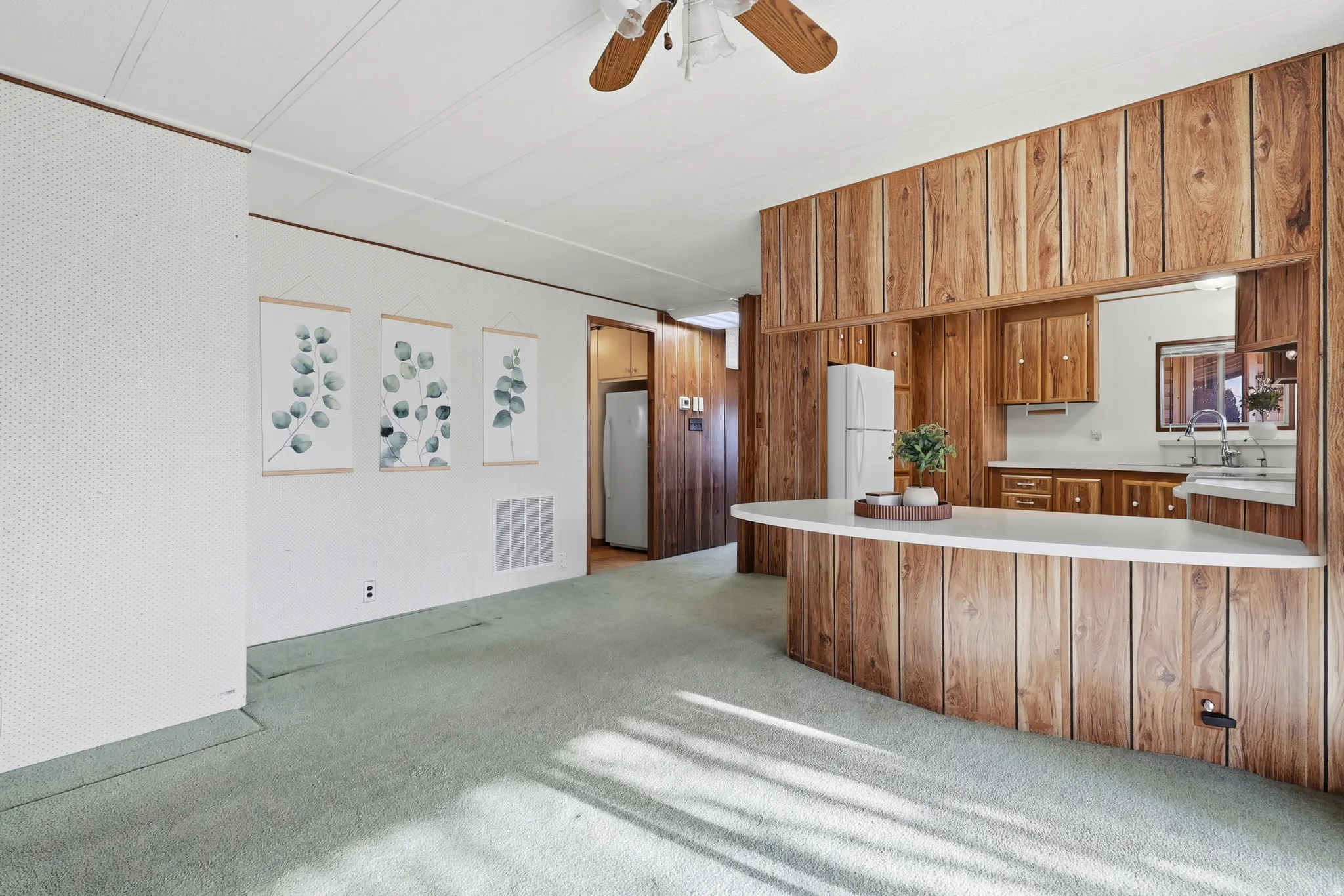 Kitchen with wood finish cabinetry, light countertops, light carpet, a peninsula, and ceiling fan