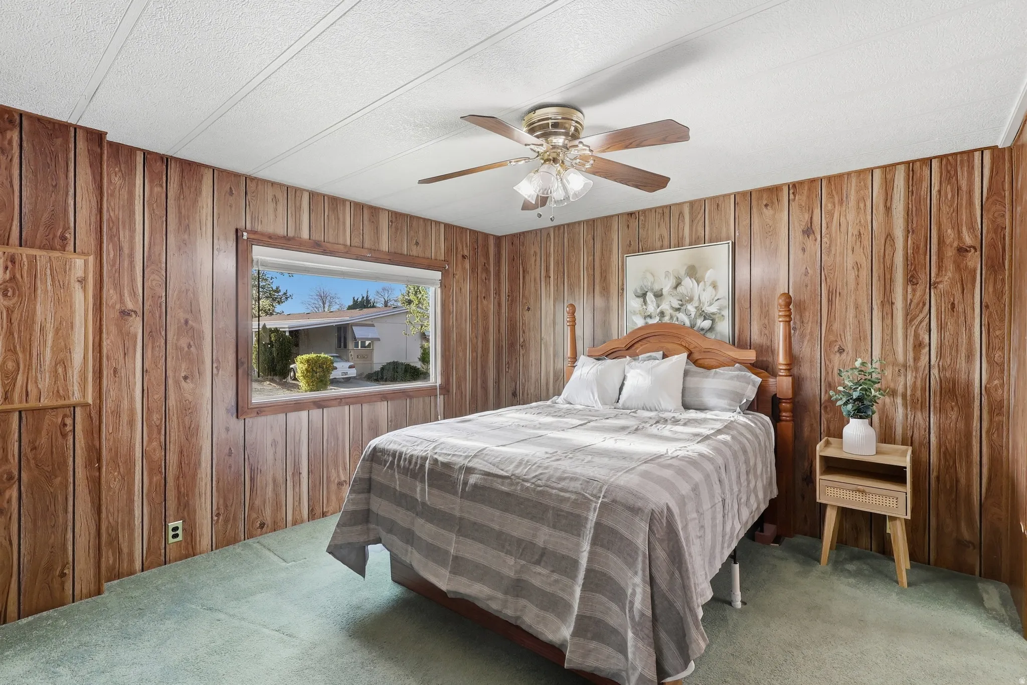 Carpeted bedroom featuring ceiling fan, wood walls, and a textured ceiling