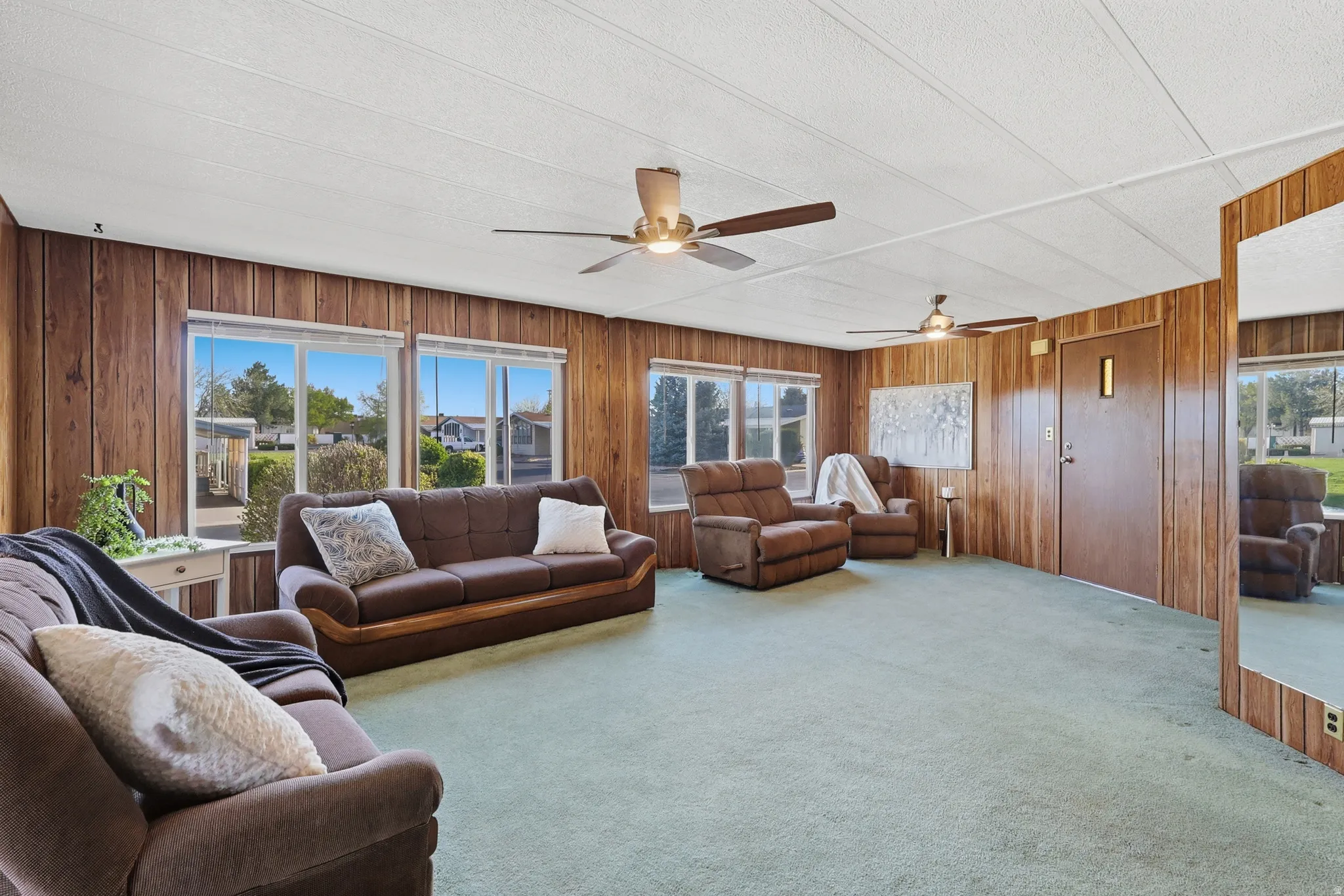 Living room with carpet flooring, wooden walls, and ceiling fan