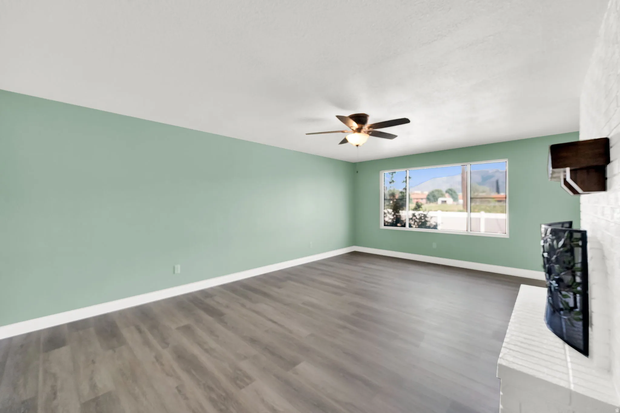 Unfurnished living room with a fireplace, dark wood-type flooring, and ceiling fan
