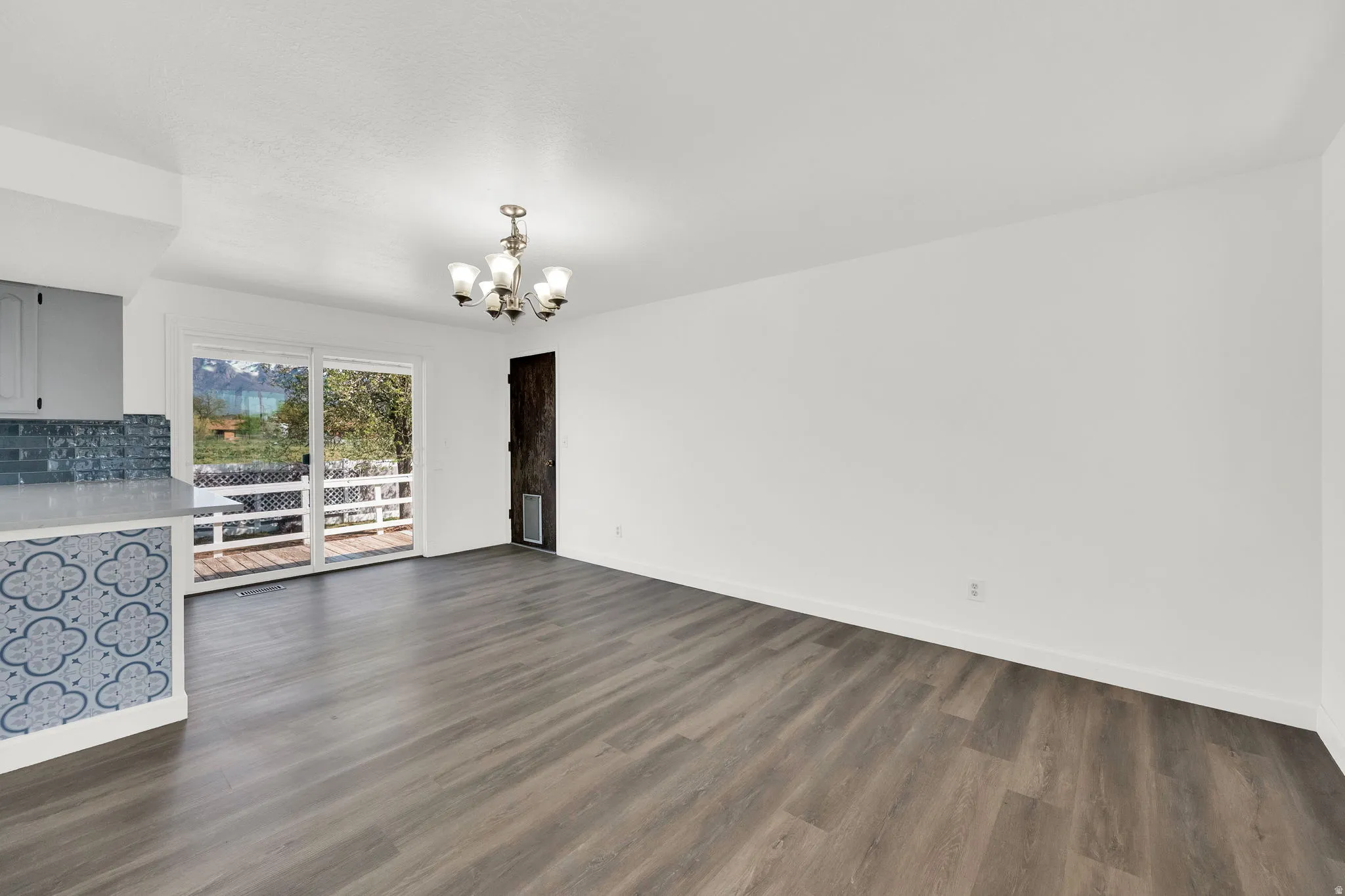 Unfurnished living room with a chandelier and dark wood-type flooring