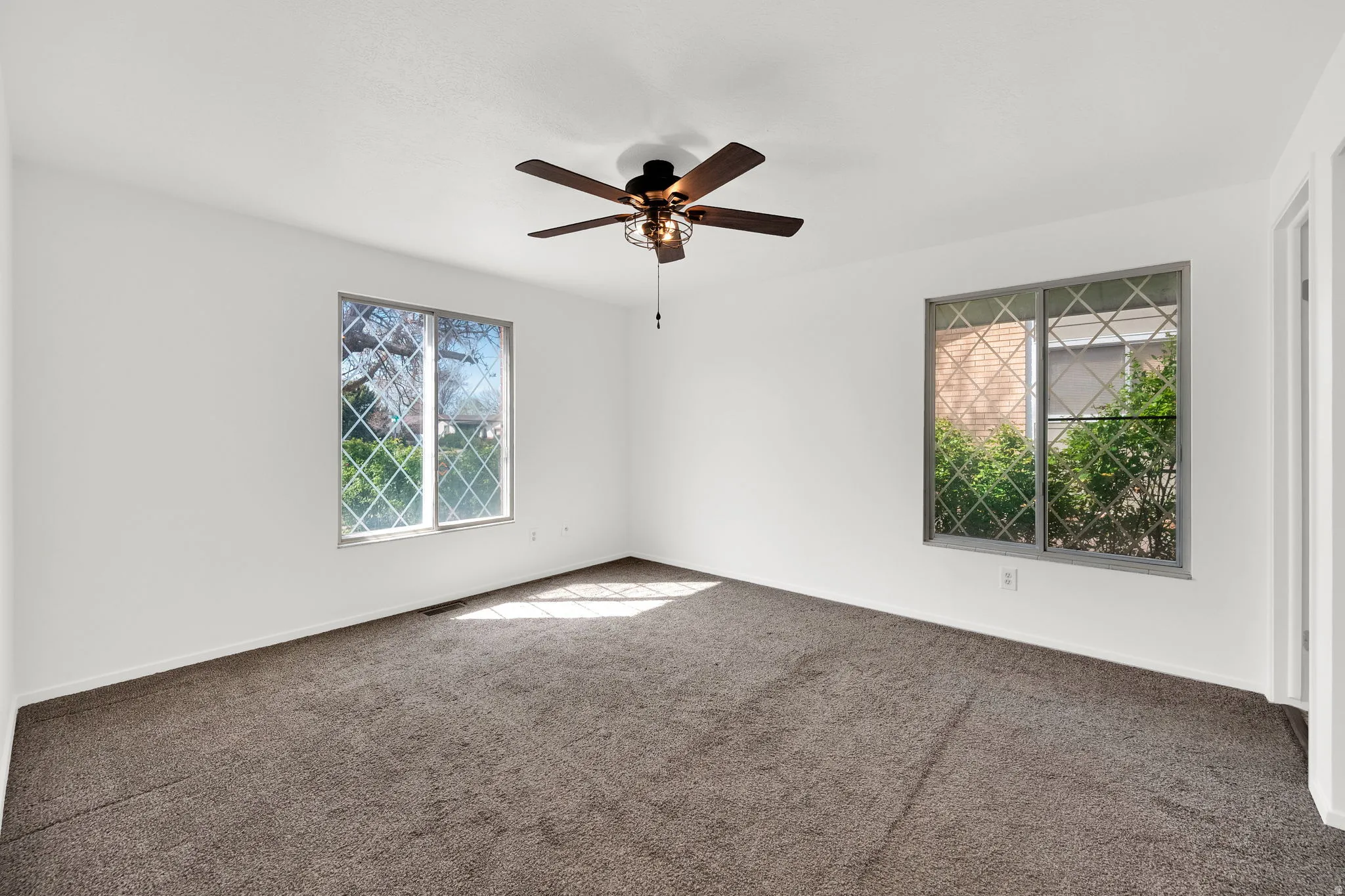 Unfurnished room with dark colored carpet and ceiling fan