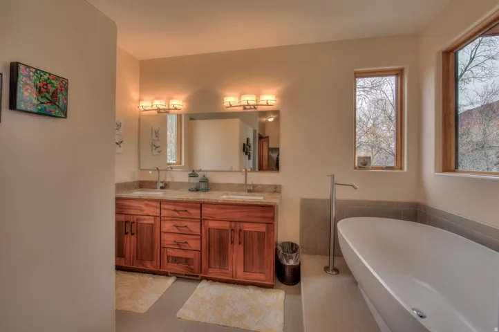 Bathroom featuring double vanity, a freestanding bath, and light tile patterned floors