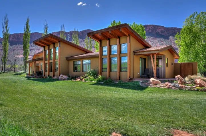 Back of house with stucco siding, a yard, and a mountain view