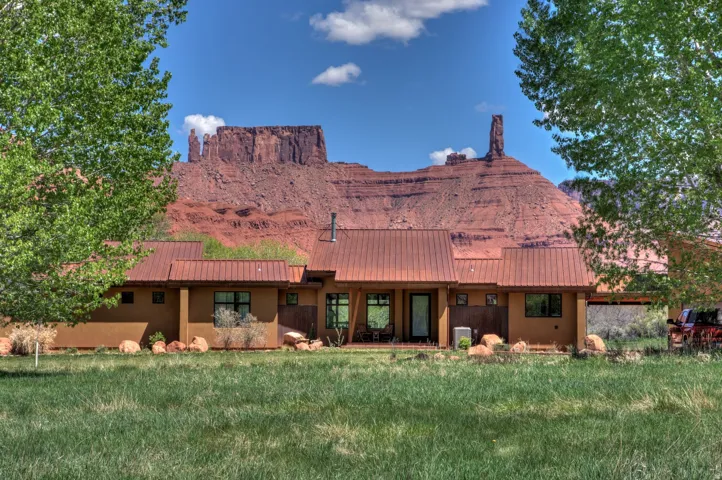 Back of property featuring stucco siding, a yard, and a metal roof