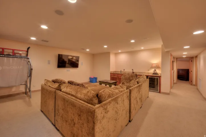 Living room featuring bar with sink, recessed lighting, beverage cooler, and light colored carpet