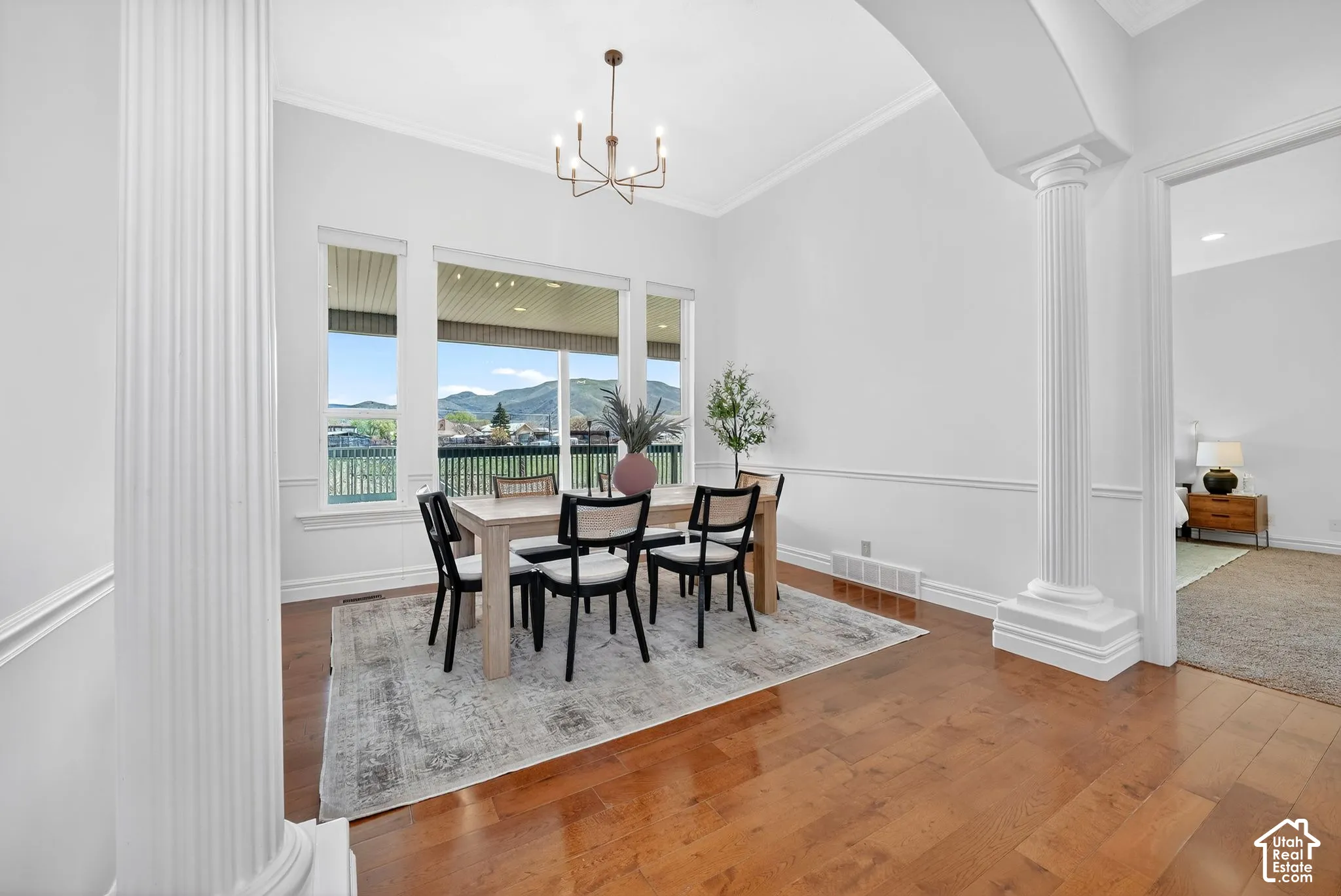 Dining area with decorative columns, a mountain view, hardwood / wood-style floors, arched walkways, and hanging lights