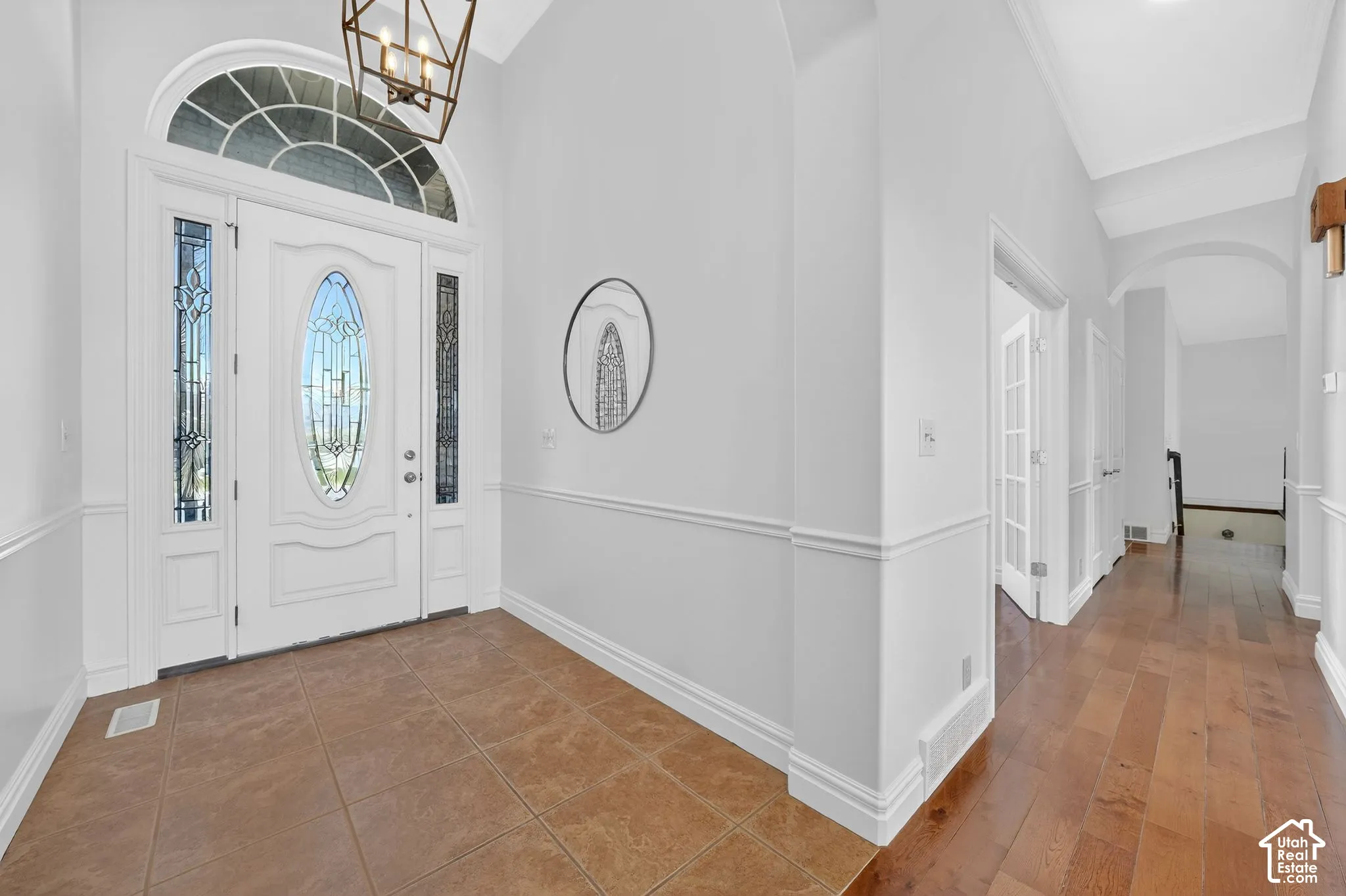 Foyer entrance with arched walkways, lofted ceiling, hanging lights, and dark wood-type flooring