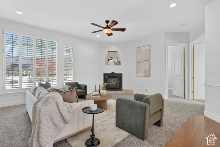 Carpeted living area featuring a ceiling fan, recessed lighting, a glass covered fireplace, and hardwood / wood-style floors