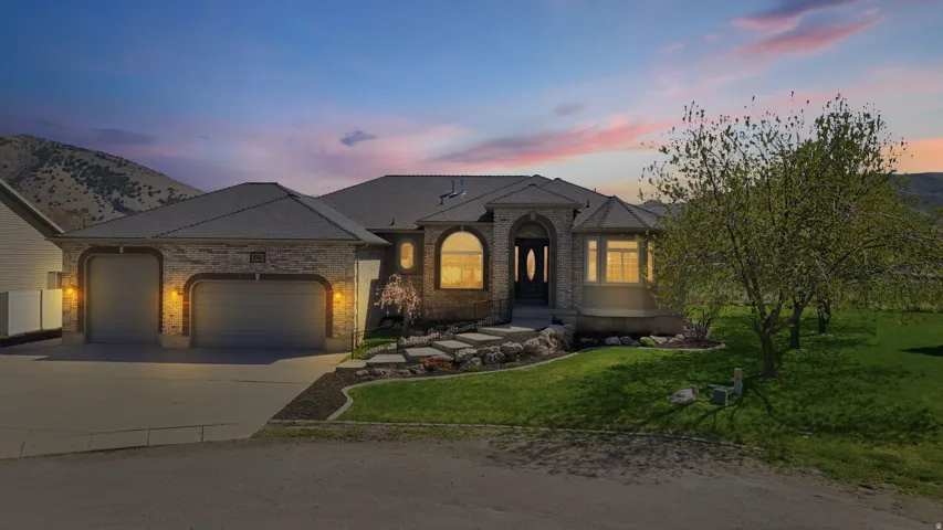 French country inspired facade featuring a yard, a garage, driveway, and brick siding