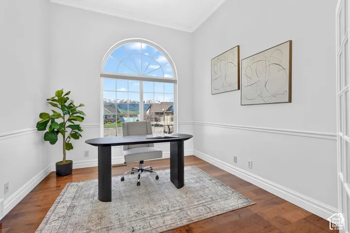 Office with dark wood-type flooring and ornamental molding