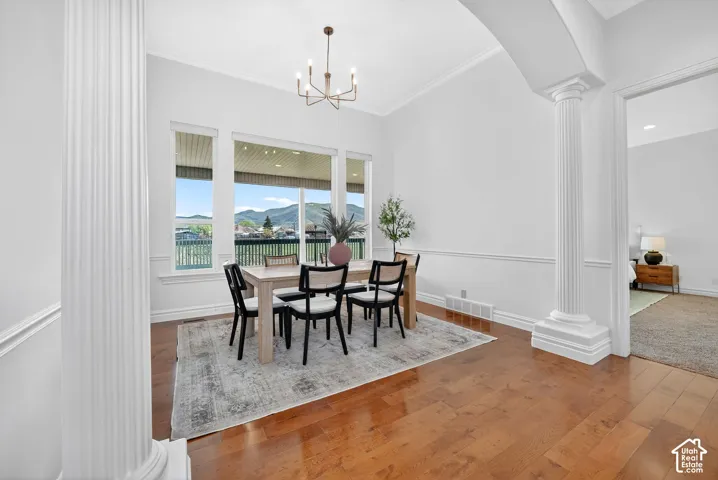 Dining area with decorative columns, a mountain view, hardwood / wood-style floors, arched walkways, and hanging lights