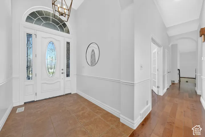 Foyer entrance with arched walkways, lofted ceiling, hanging lights, and dark wood-type flooring