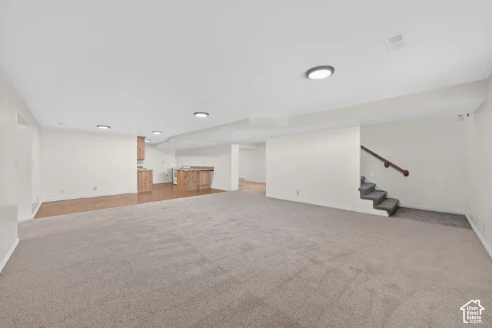 Finished basement featuring stairway and light carpet