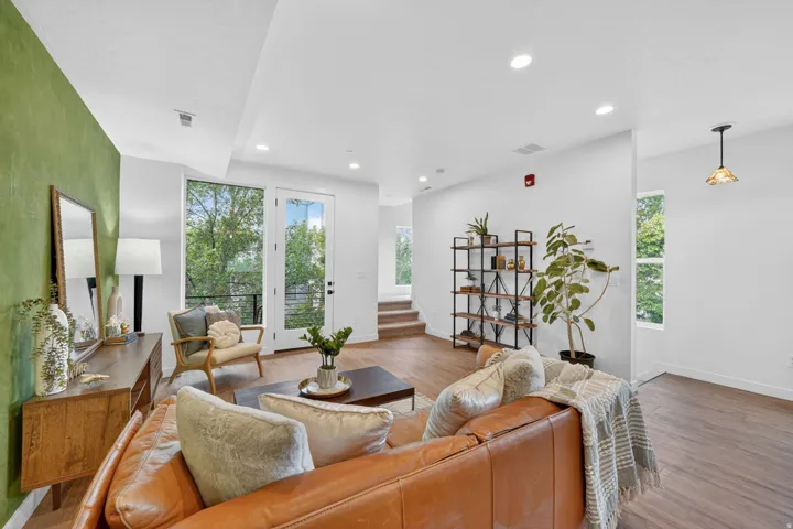 Open-concept living space featuring wood-finish flooring, recessed lighting, and a prominent green accent wall