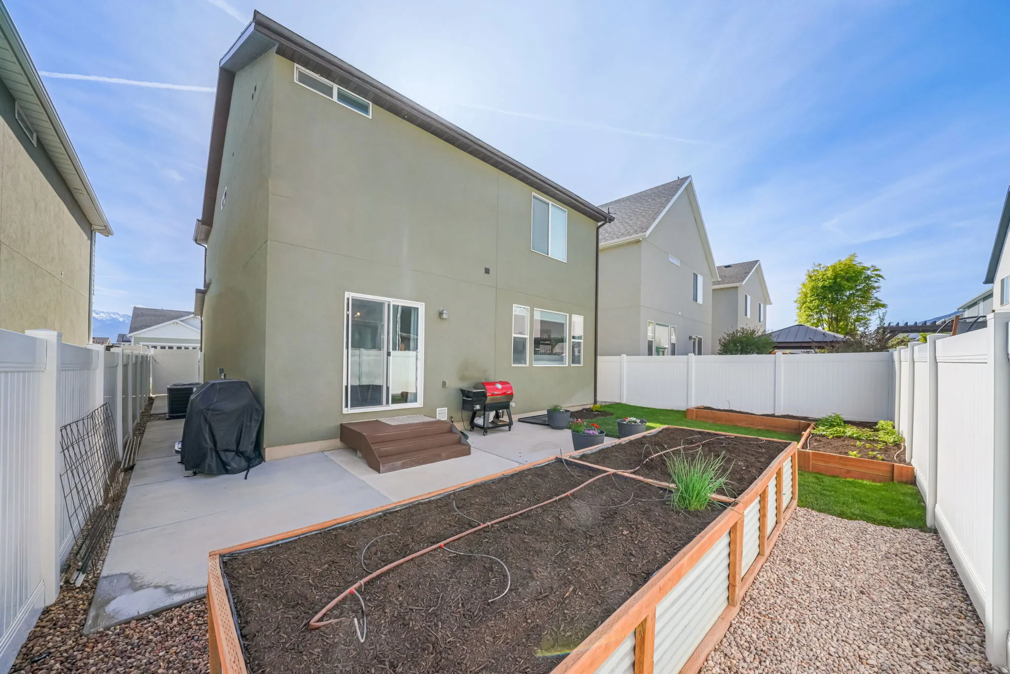 Rear view of property featuring a patio area, stucco siding, a fenced backyard, and a garden