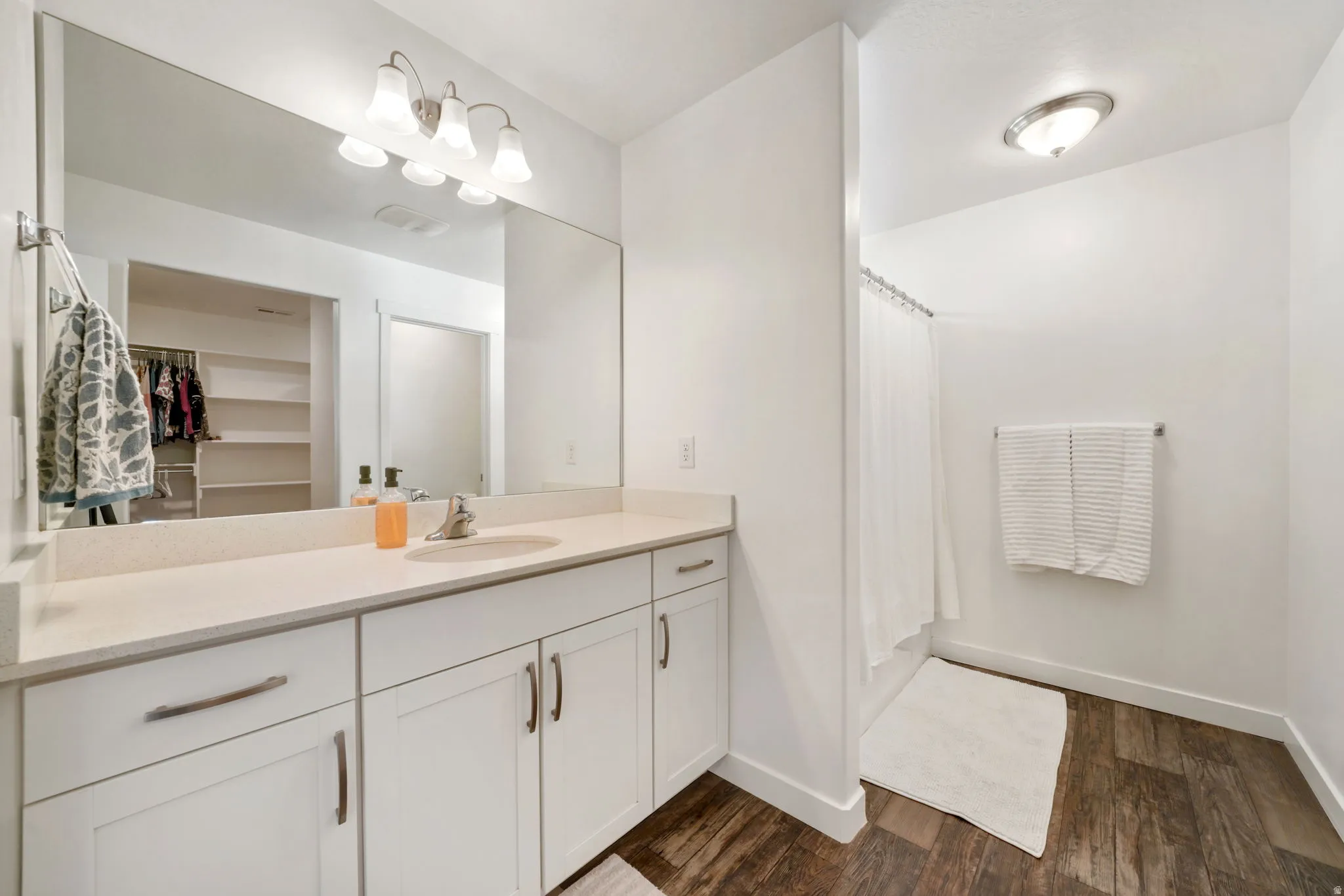 Bathroom with vanity, dark wood-style flooring, shower / bath combo, and a walk in closet