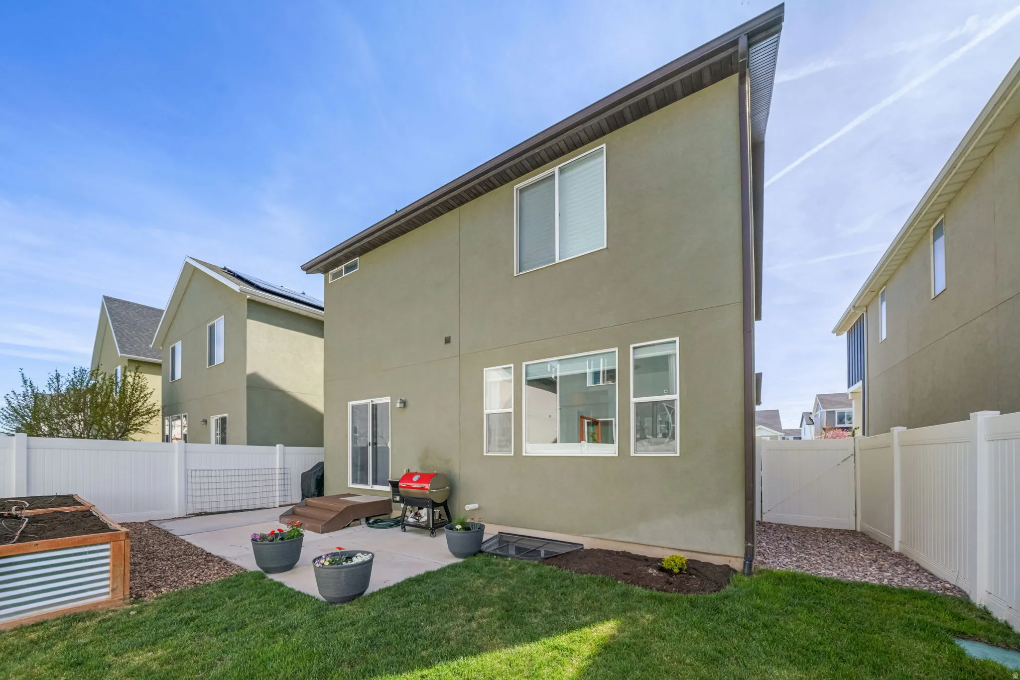 Rear view of property with a patio, stucco siding, a fenced backyard, and a garden