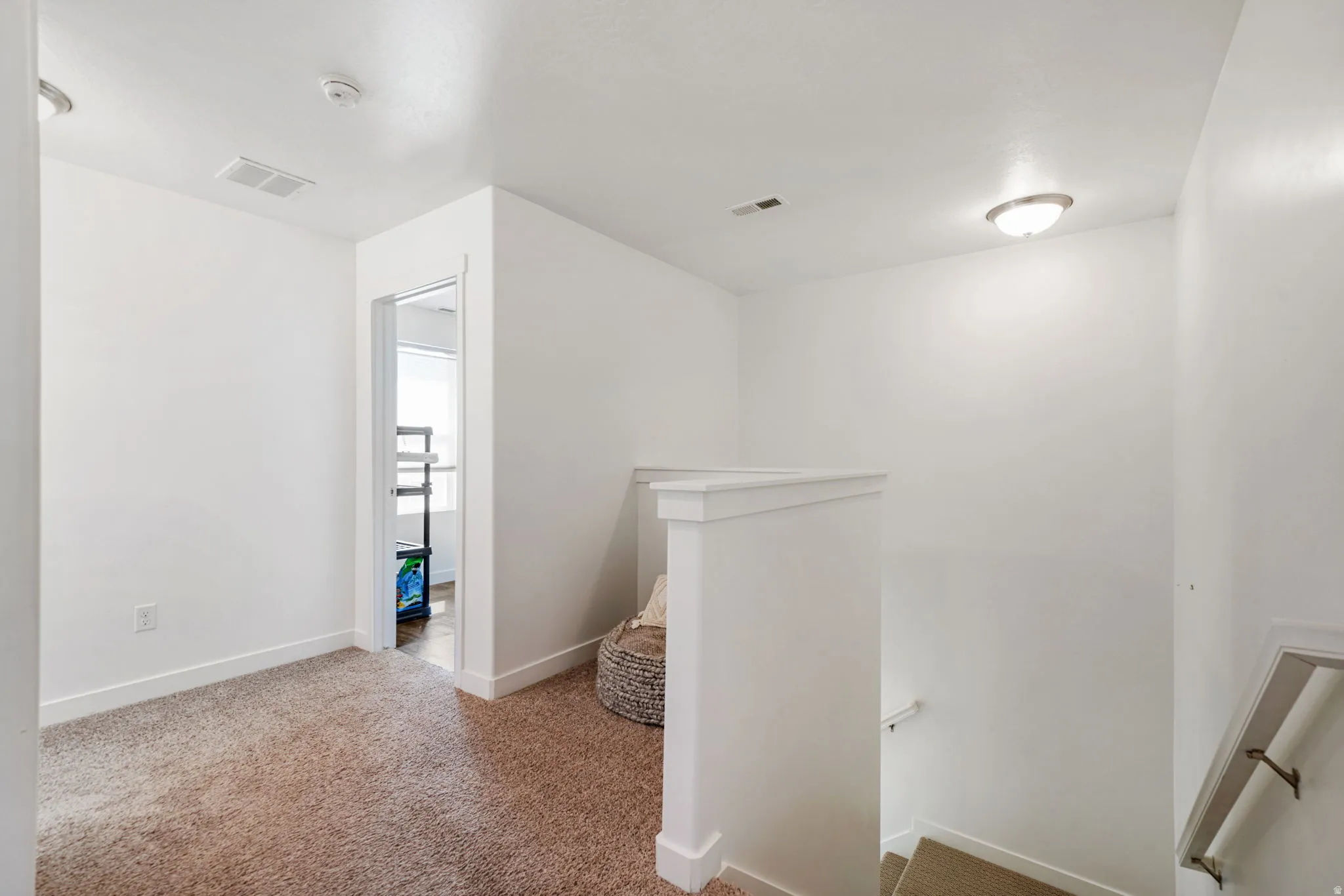 Hallway with an upstairs landing and light colored carpet
