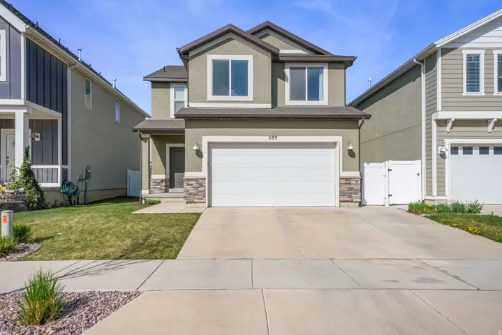 View of front of house featuring a gate, stone siding, stucco siding, and driveway