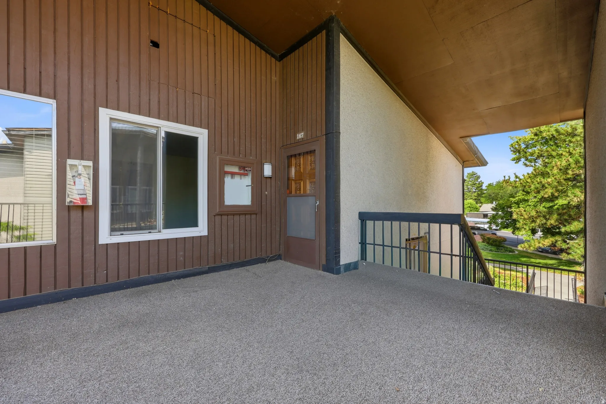 Outdoor balcony with textured flooring and a dark metal railing