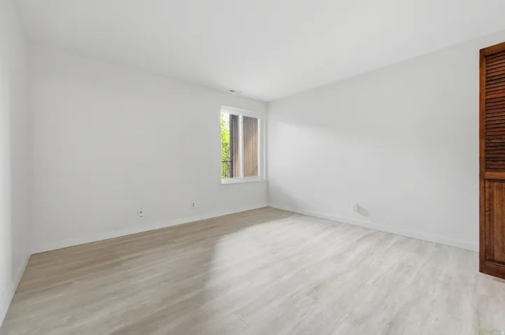 Bright interior space featuring light wood-finish flooring, white baseboards, and white painted walls