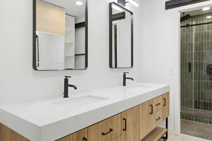 Double vanity featuring light wood-finish cabinetry, white countertops, and matte black fixtures