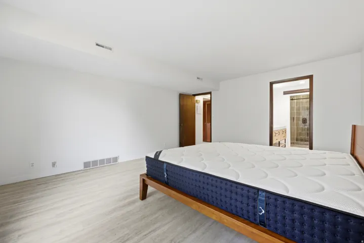 Spacious room featuring light wood-finish flooring and white painted walls