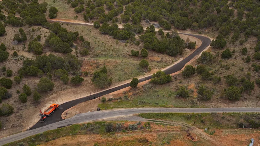 Winding paved road ascending through a natural, undeveloped landscape with scattered shrubbery and trees