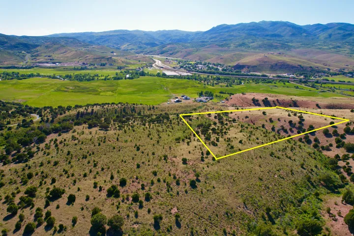 Aerial view of sparsely populated area featuring property parcel outlined and a mountain backdrop
