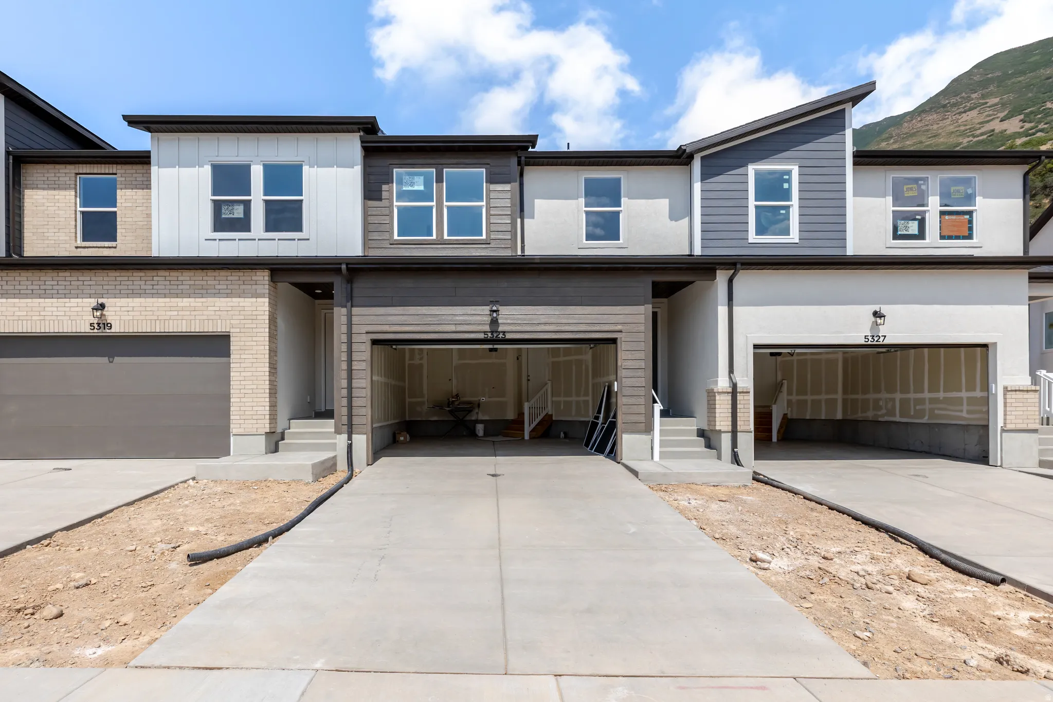 Modern townhome exterior featuring a combination of light brick, stucco, and horizontal siding