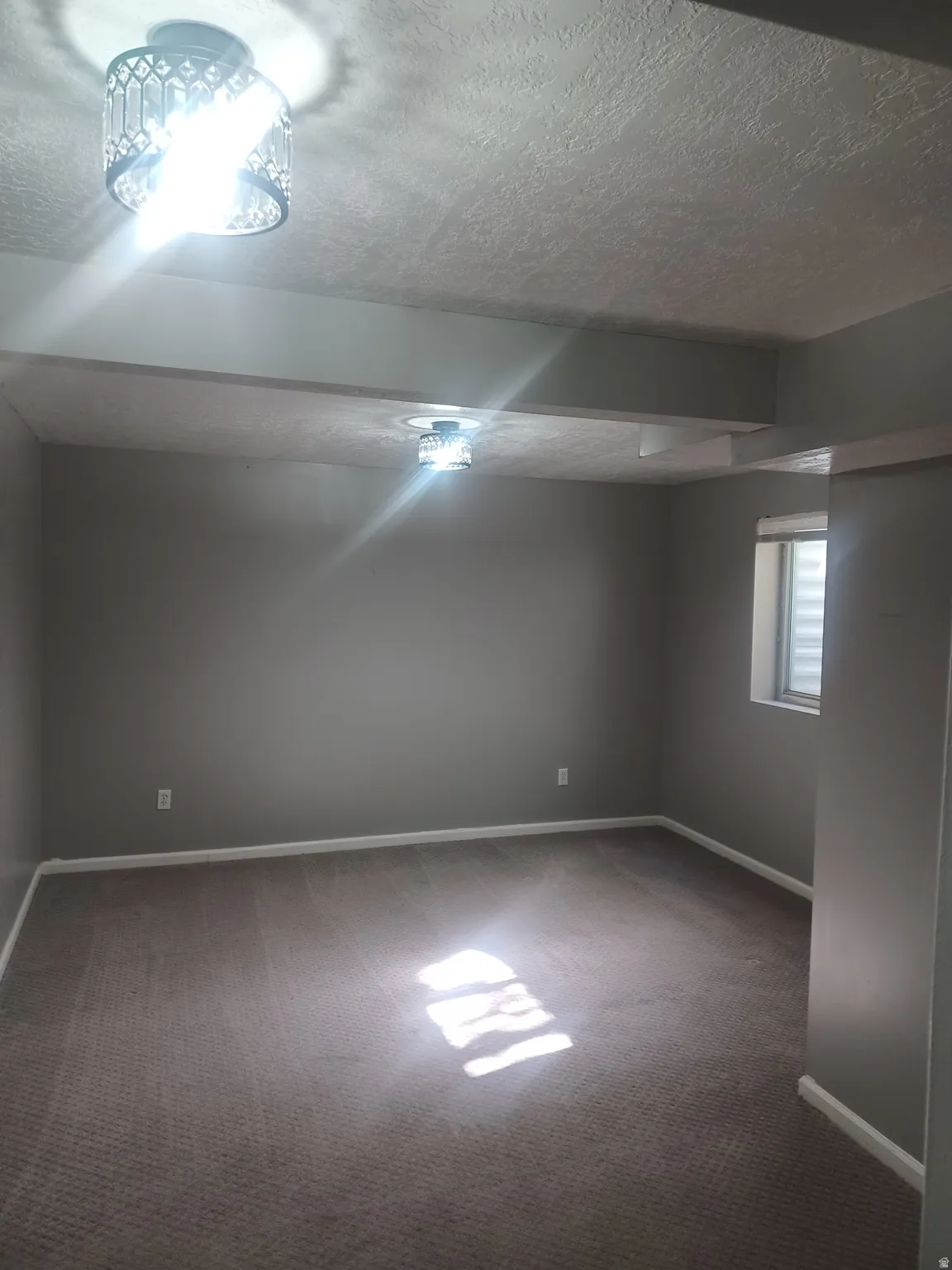 Basement Bedroom featuring a textured ceiling and light carpet