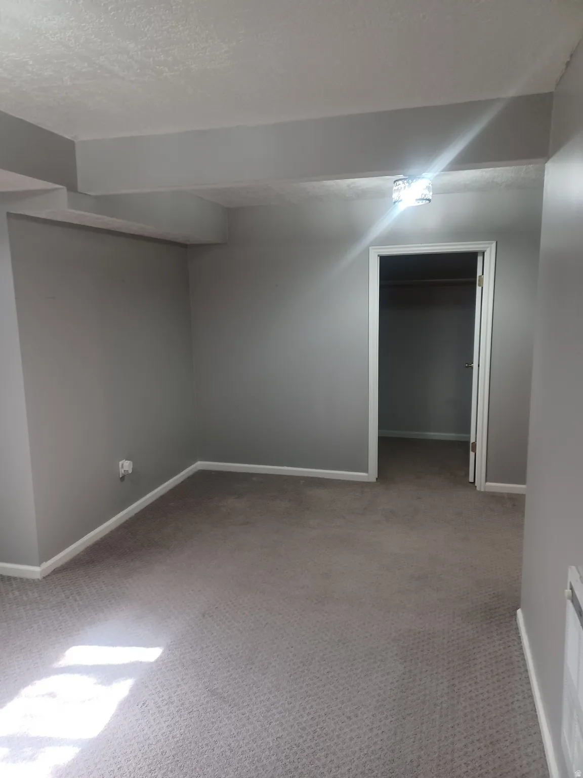 Basement Bedroom 2 Finished below grade area featuring light carpet and a textured ceiling