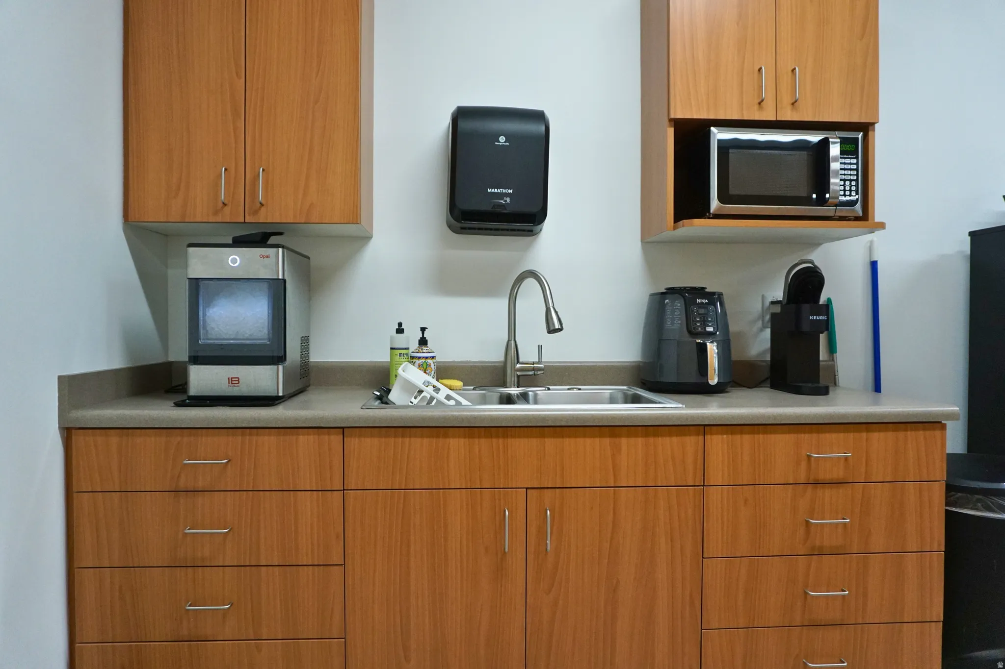 Kitchen with stainless steel microwave, light countertops, and wood finish cabinetry