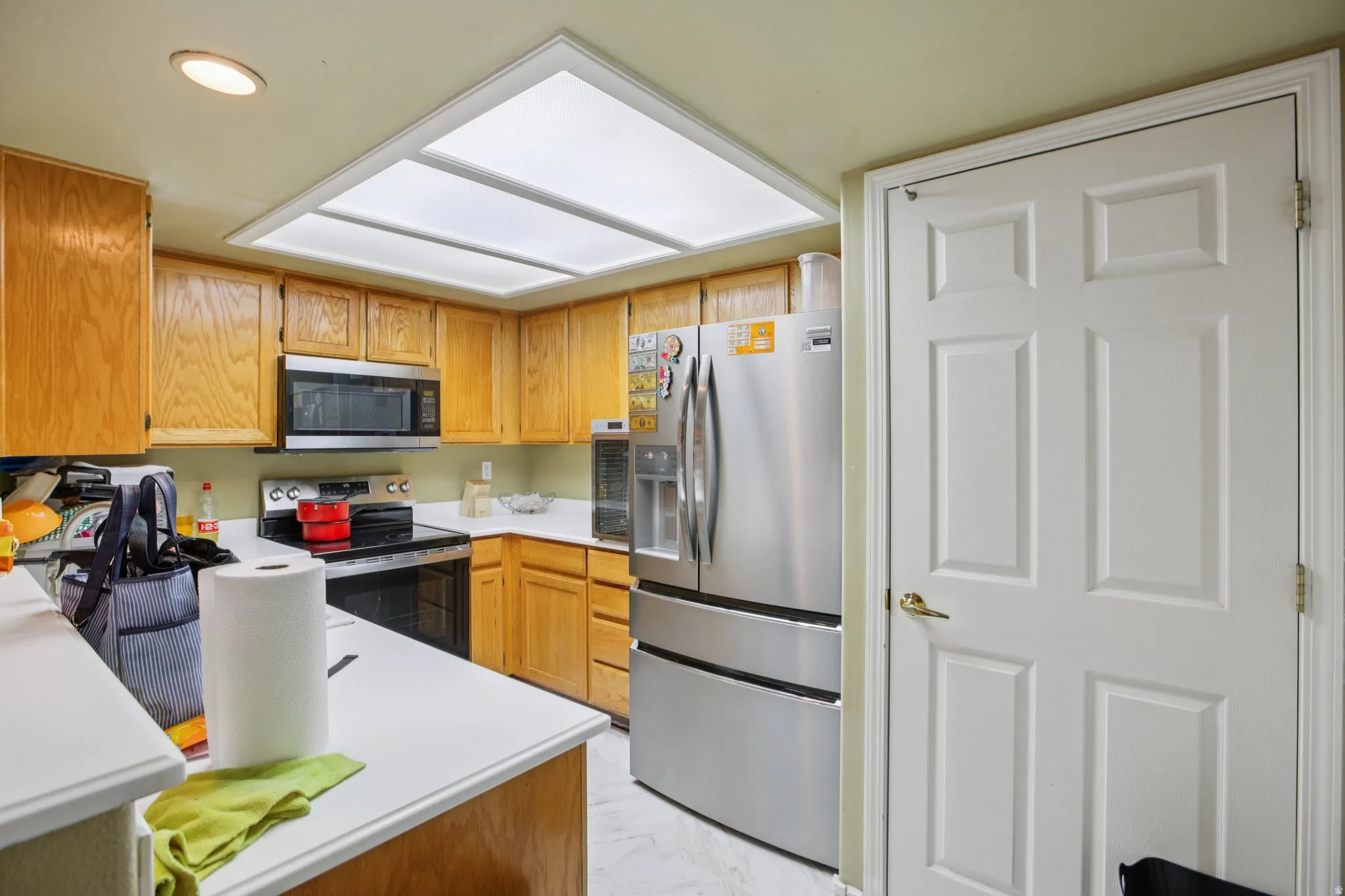 Kitchen with stainless steel appliances, light countertops, wood finish cabinets, and recessed lighting