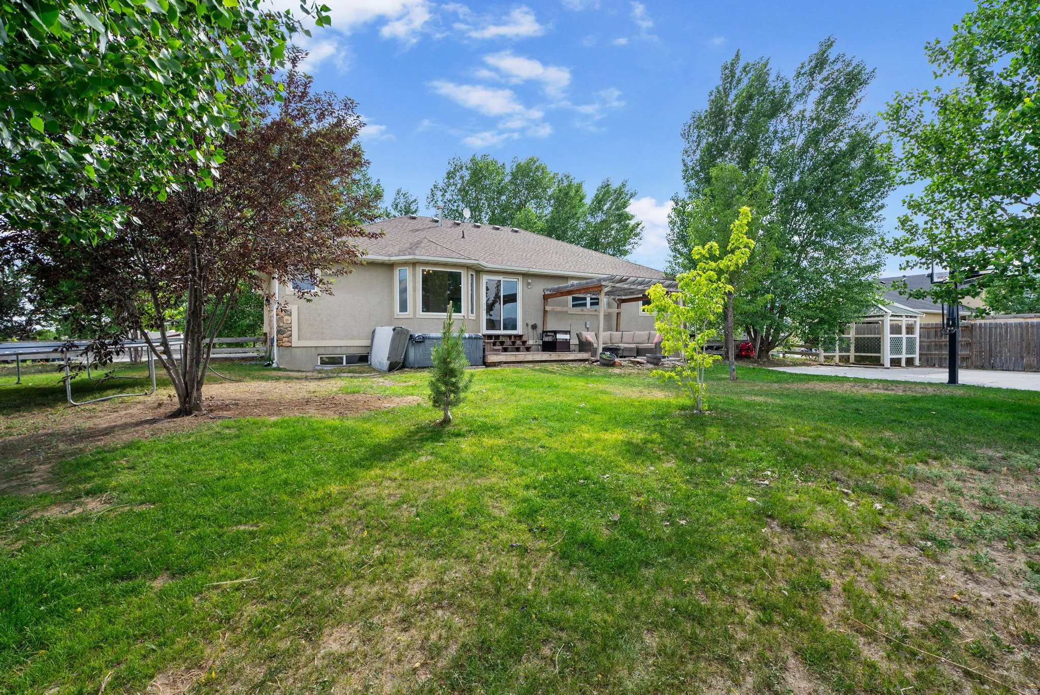 Back of house with a trampoline, a fenced backyard, and a patio
