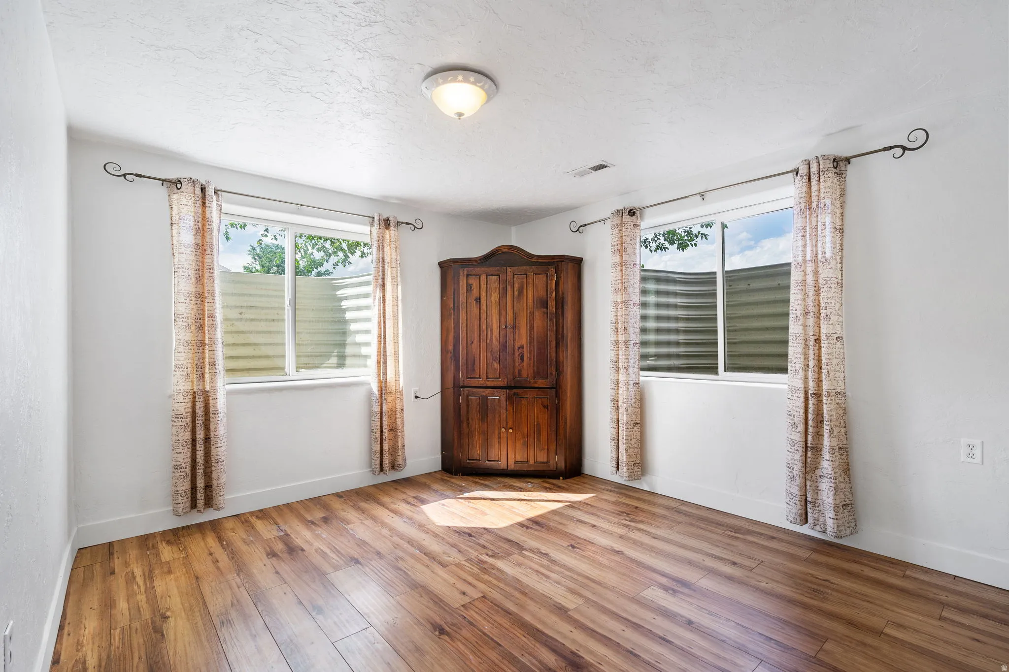Empty room featuring light wood-style floors and a textured ceiling