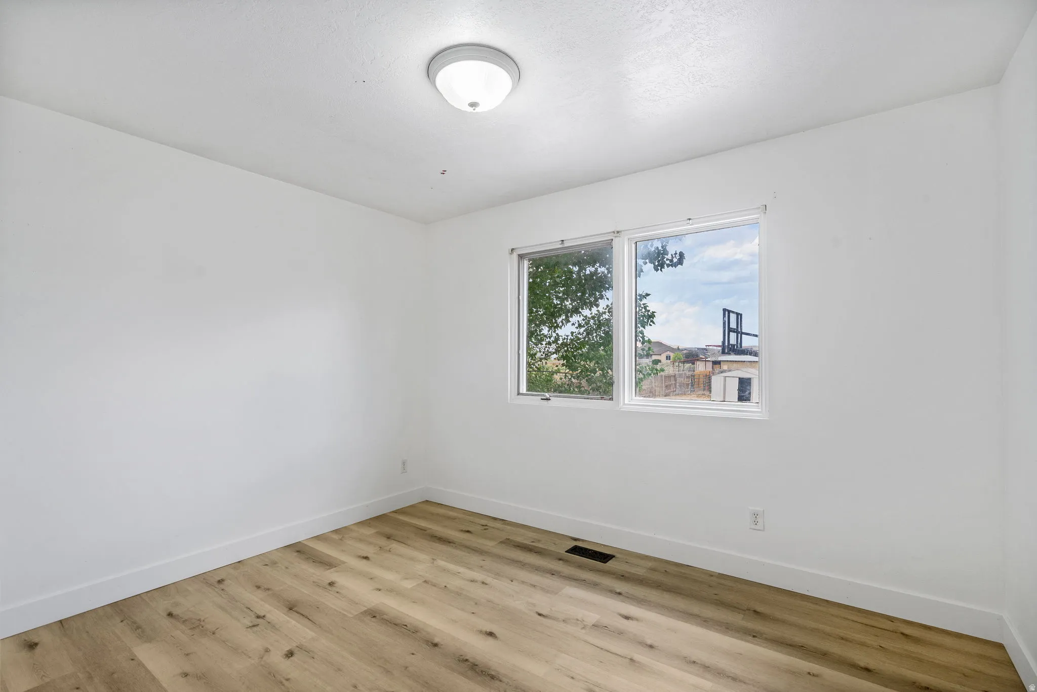Spare room featuring baseboards and light wood-type flooring