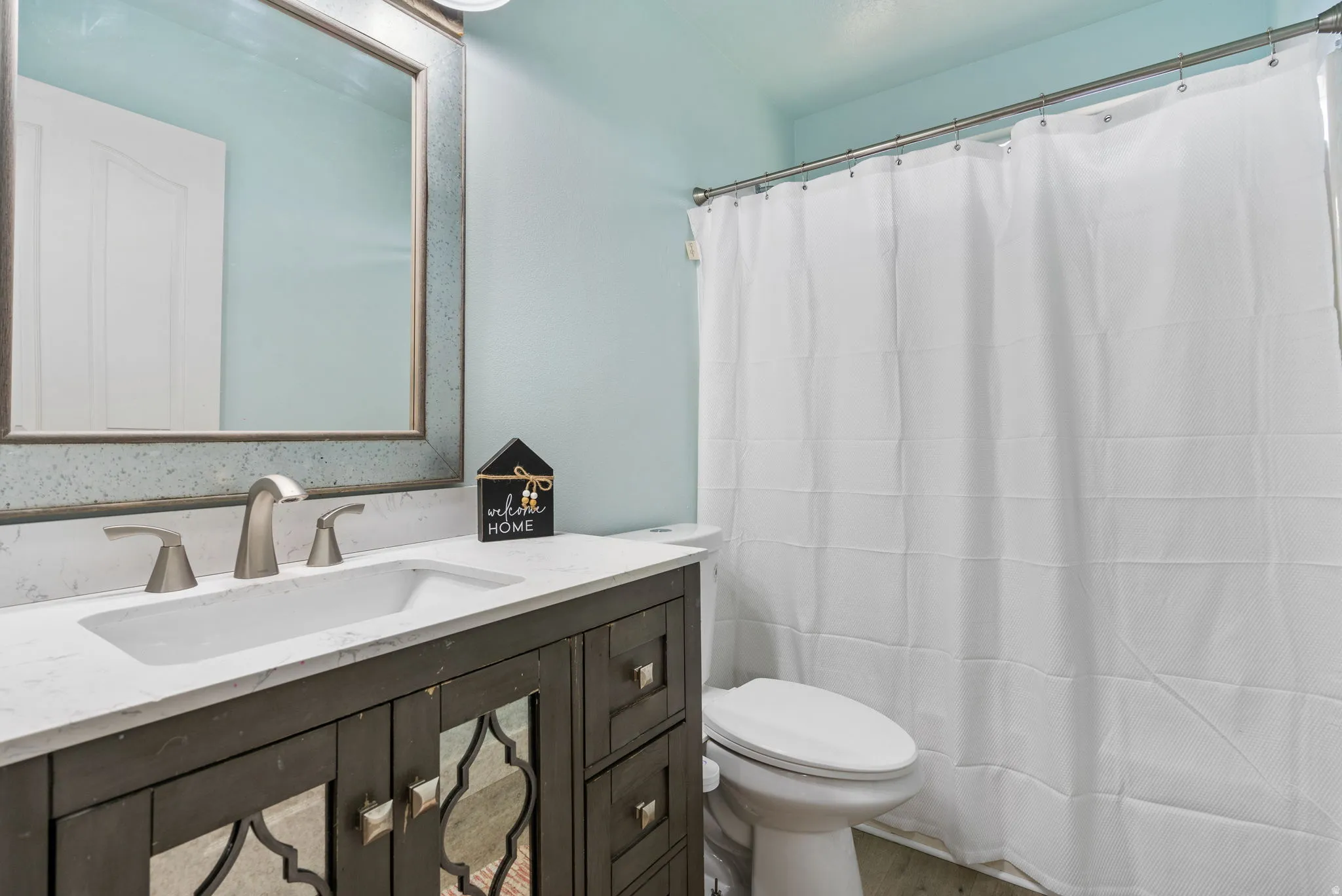 Full bath featuring vanity, a shower with shower curtain, and wood finished floors